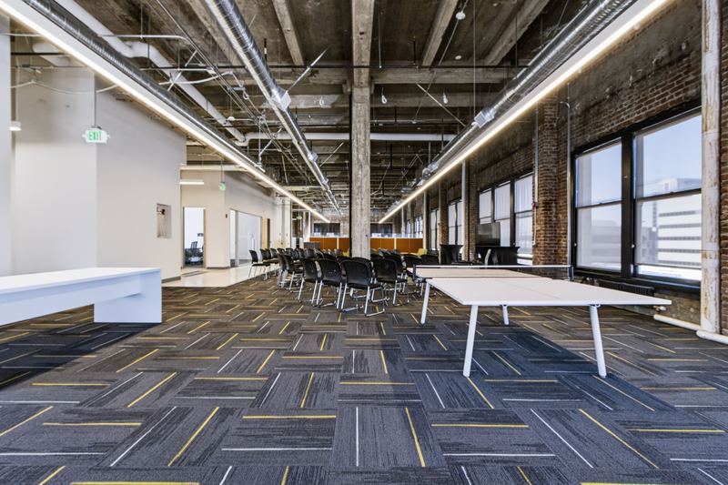 Open loft floor with long tables, brick walls and tall windows at 1440 Broadway