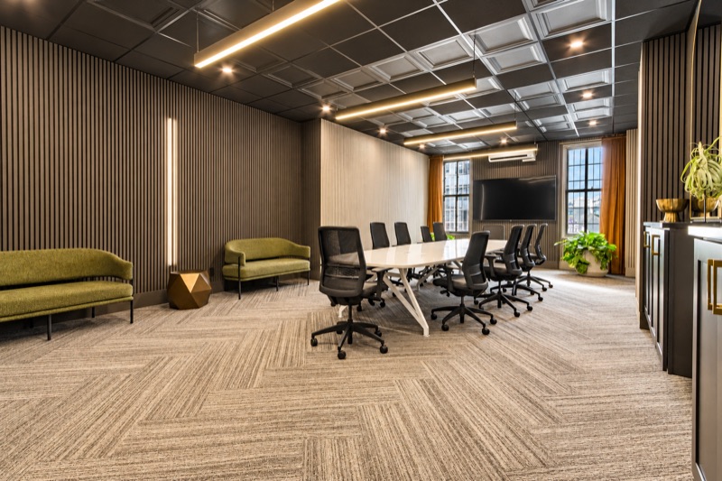 Conference room with a long white table, slatted wood walls and tall windows
